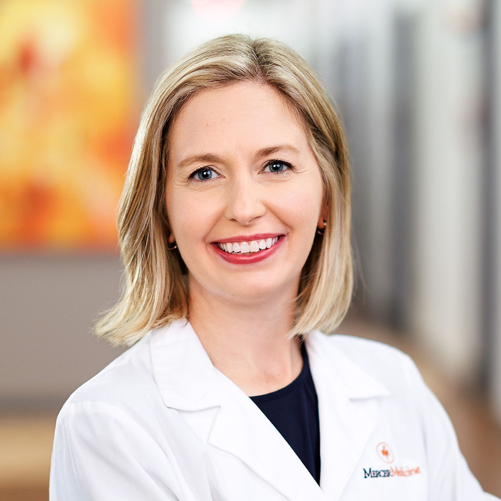 Helen King, MD, infectious disease specialist, smiling in a clinic hallway while wearing a white coat.